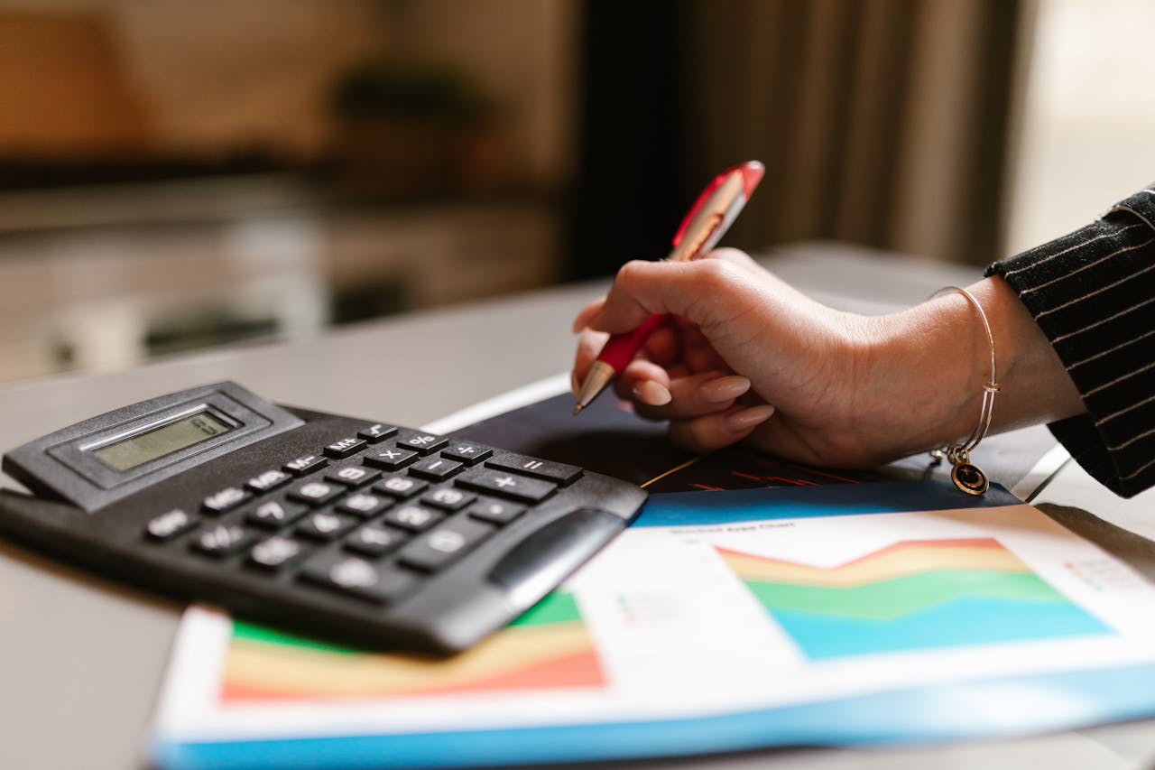A business professional uses a calculator and documents during a workspace task.