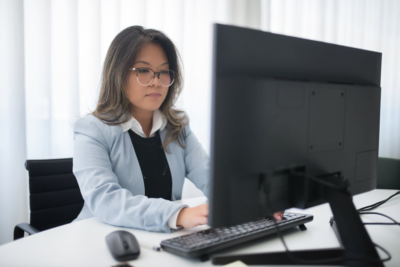 Confident businesswoman focused on work at desk with computer in modern office.